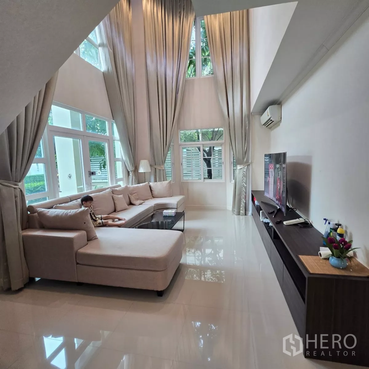 Detached House for rent in Mueang Pathum Thani, Pathum Thani - Grand living area with double-height ceiling and glossy tiled floors.