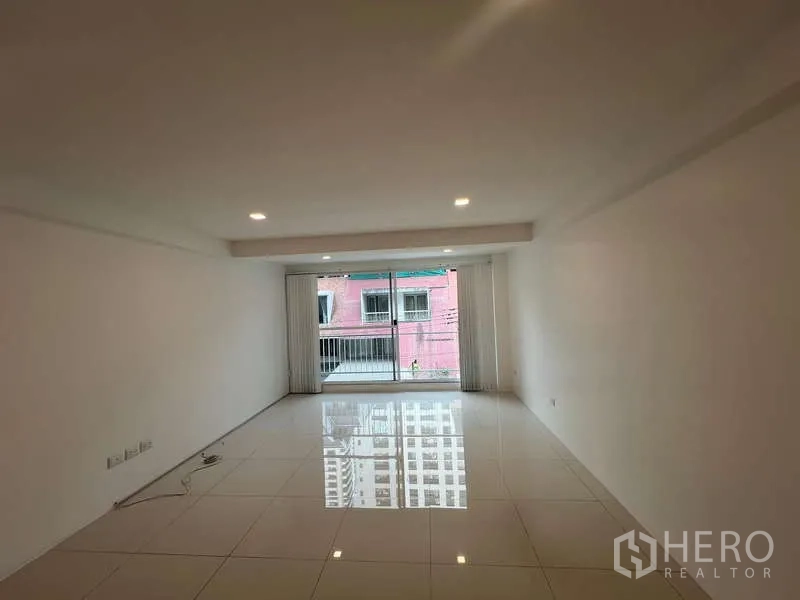 带办公室的家 出租在Khlong Toei, Bangkok - 宽敞白色客厅，筒灯照明，推拉落地门通向阳台。