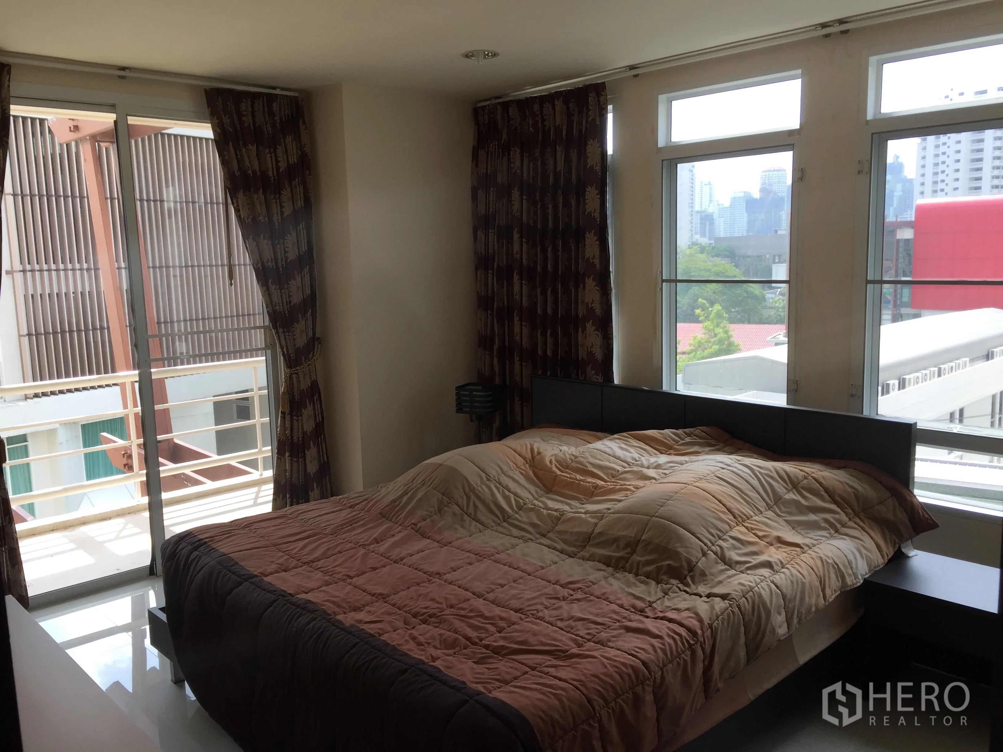 公寓 出租或出售在Watthana, Bangkok - 明亮卧室，推拉玻璃门连通阳台，远眺城市天际线。