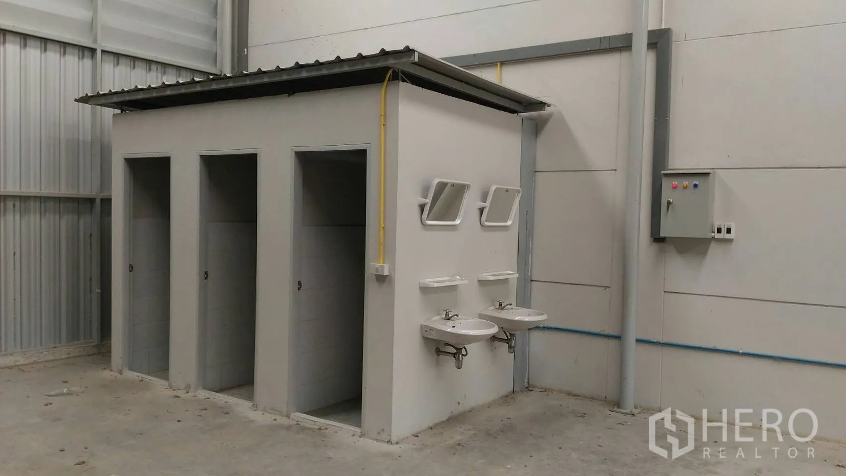 Warehouse for rent in Lam Luk Ka, Pathum Thani - On-site restroom block inside the warehouse with stalls, twin sinks, mirrors and an electrical control panel.
