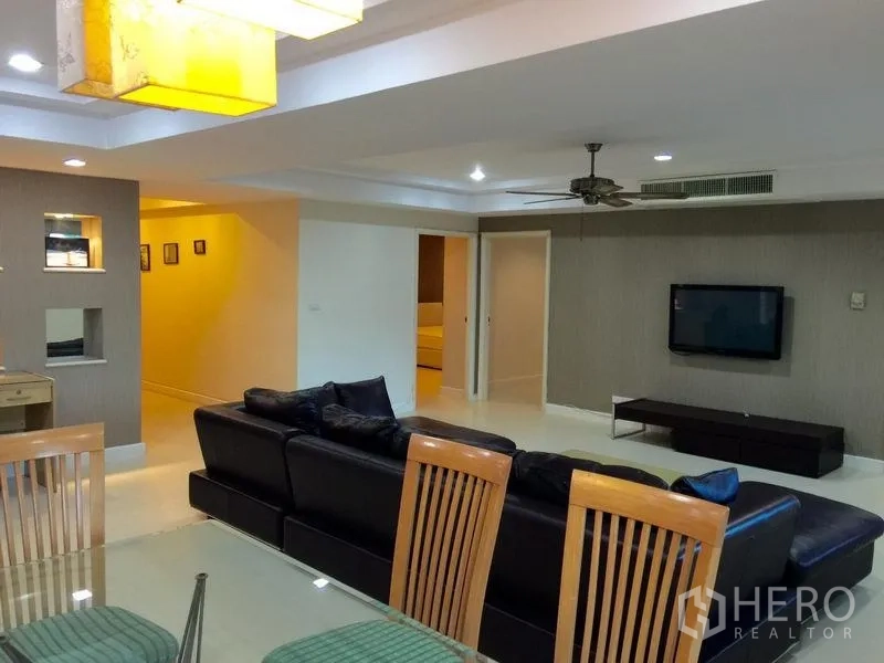 公寓 出租在Watthana, Bangkok - 客厅配吊扇、壁挂电视与温暖吊灯的用餐空间。