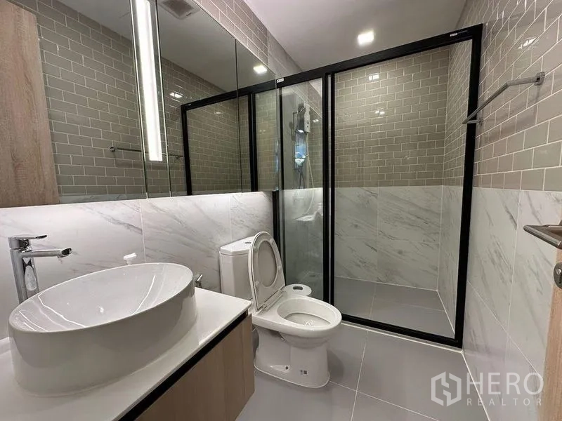 คอนโด ให้เช่าในRatchathewi, Bangkok - ห้องน้ำร่วมสมัย อ่างล้างหน้าแบบวางบนเคาน์เตอร์ โถสุขภัณฑ์ และตู้ชาวเวอร์กระจกบุผนังกระเบื้องสีเทา