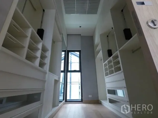 Apartment for rent in Khlong Toei, Bangkok - Spacious walk-in closet featuring custom cabinetry, drawers, and a full-height window.