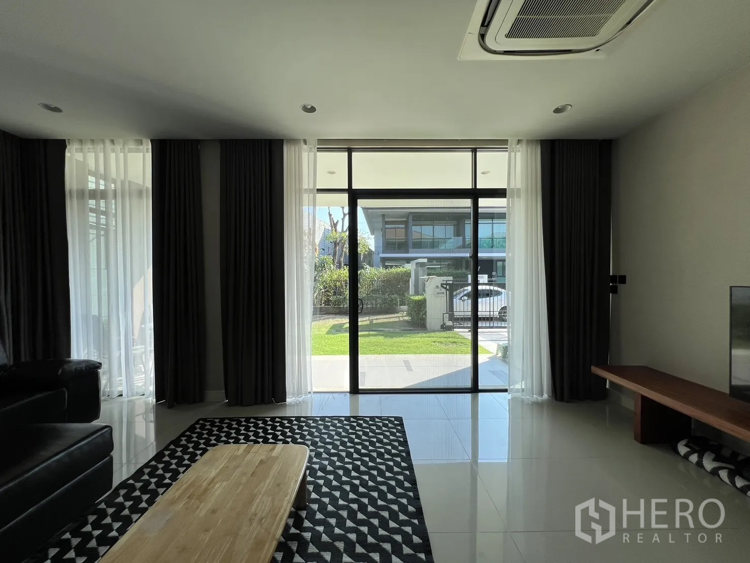 独立式住宅 出租或出售在Bang Kapi, Bangkok - 起居区通过落地玻璃通向露台，自然光与绿意充盈。