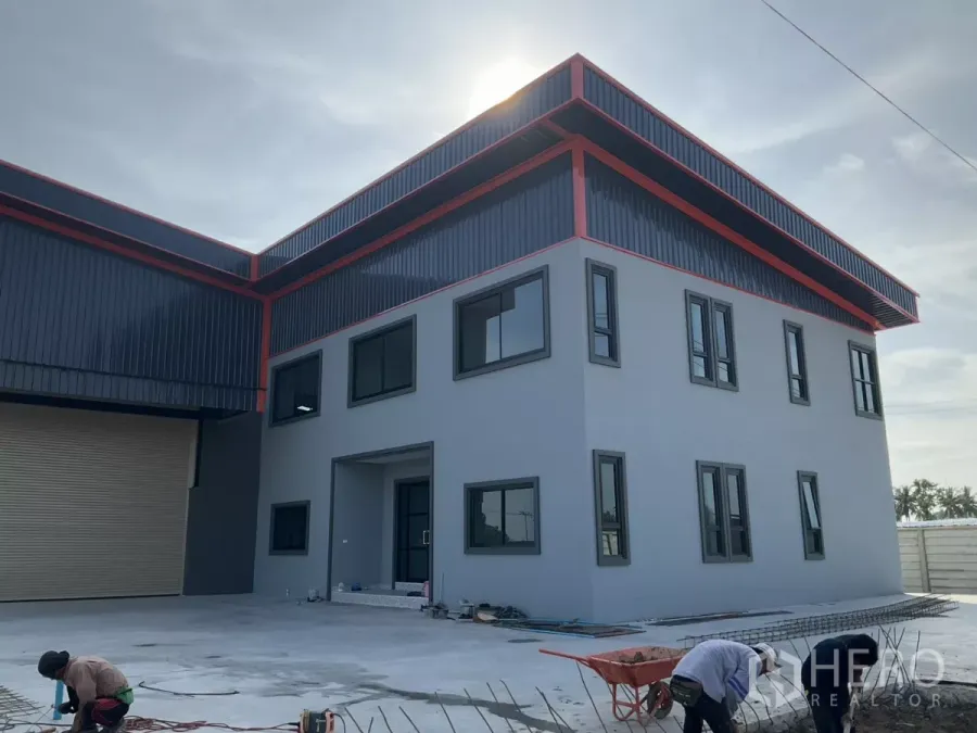 Factory for sale in Samut Sakhon - Angle view of a newly built factory with a two-storey office block, metal roof and wide concrete yard.