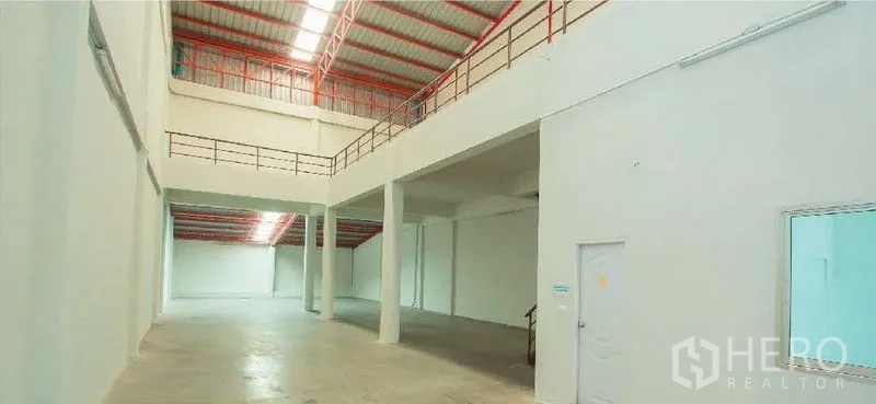 Factory for rent in Phra Samut Chedi, Samut Prakan - Bright, double-height warehouse interior with open floor, mezzanine and safety railings.