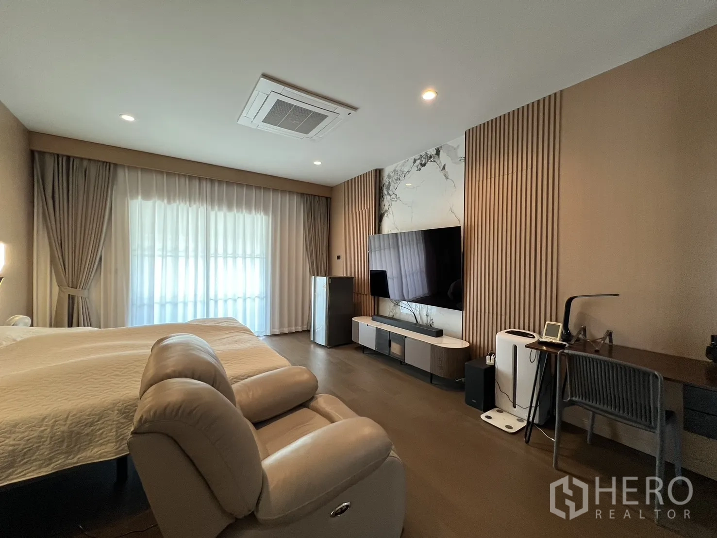 独立式住宅 出租或出售在Mueang Pathum Thani, Pathum Thani - 主卧宽敞，躺椅、电视墙与落地窗帘。