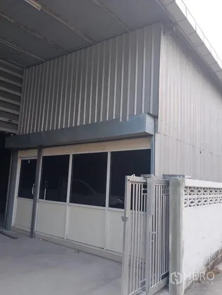 货栈 出租在Huai Khwang, Bangkok - 仓库前部带玻璃推拉门的办公室入口，旁有金属栅门。