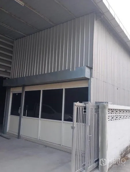 货栈 出租在Huai Khwang, Bangkok - 仓库前部带玻璃推拉门的办公室入口，旁有金属栅门。