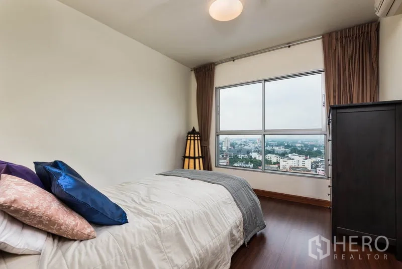 Condominium for rent in Bang Na, Bangkok - Second bedroom with large window overlooking Bangkok cityscape.