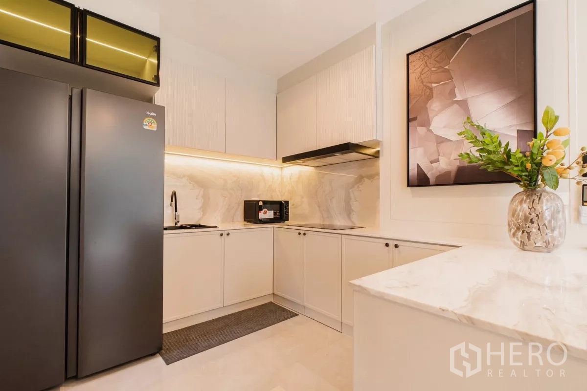 Detached House for rent or sale in Prawet, Bangkok - Modern U-shaped kitchen with white cabinets, marble backsplash and black fridge