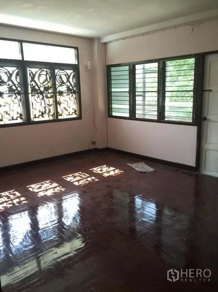 Detached House for rent in Chatuchak, Bangkok - Bedroom with security grille windows, polished wood floor and a white door.