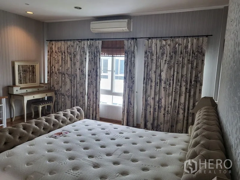 联排别墅 出租在Wang Thonglang, Bangkok - 明亮卧室，花卉窗帘、梳妆台与壁挂空调