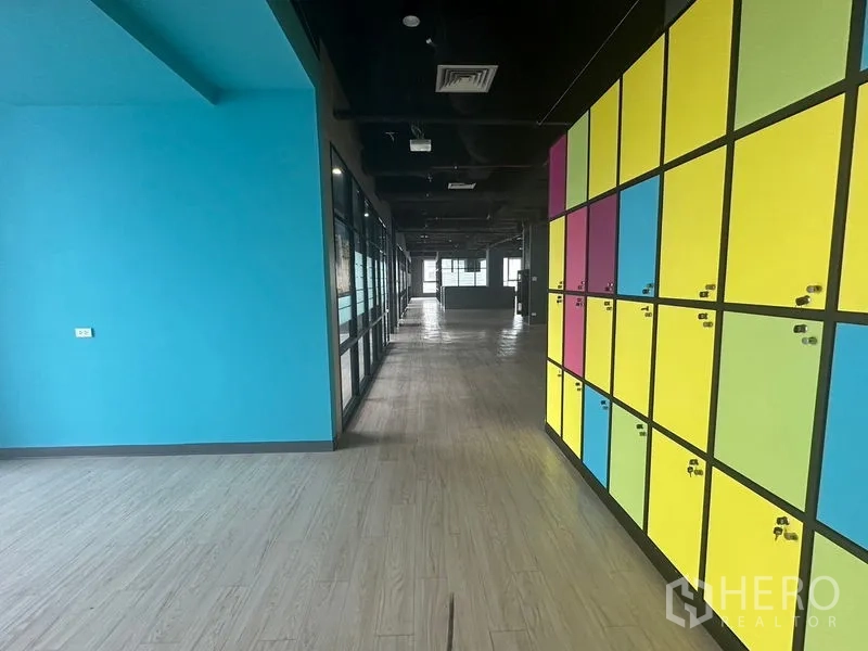 Office Space for rent in Bang Rak, Bangkok - Breakout zone with vibrant lockers and a turquoise wall beside the main workspace.