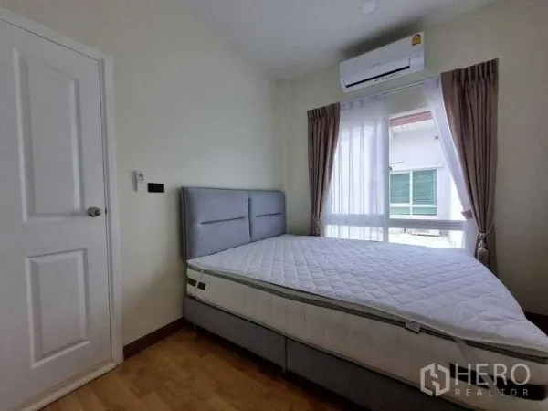 联排别墅 出租在Wang Thonglang, Bangkok - 卧室带大窗、纱帘、空调与灰色床。