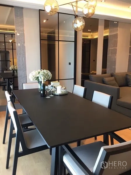 公寓 出租在Watthana, Bangkok - 餐厅六人餐桌，现代吊灯与镜面墙。