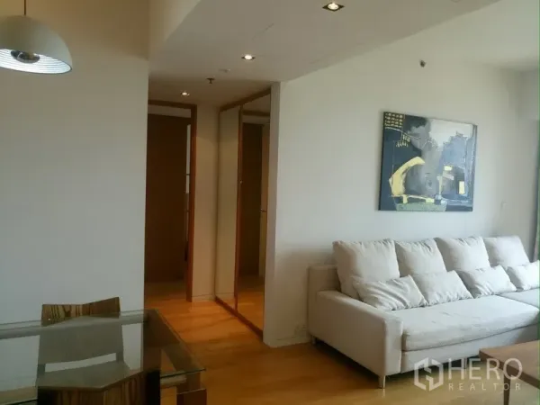 Condominium for rent in Sathon, Bangkok - Open-plan living and dining area with a glass table and hallway leading to the bedrooms.