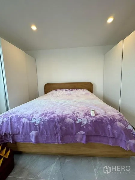 Condominium for rent or sale - Bedroom with queen bed, purple duvet, and fitted wardrobes on both sides.