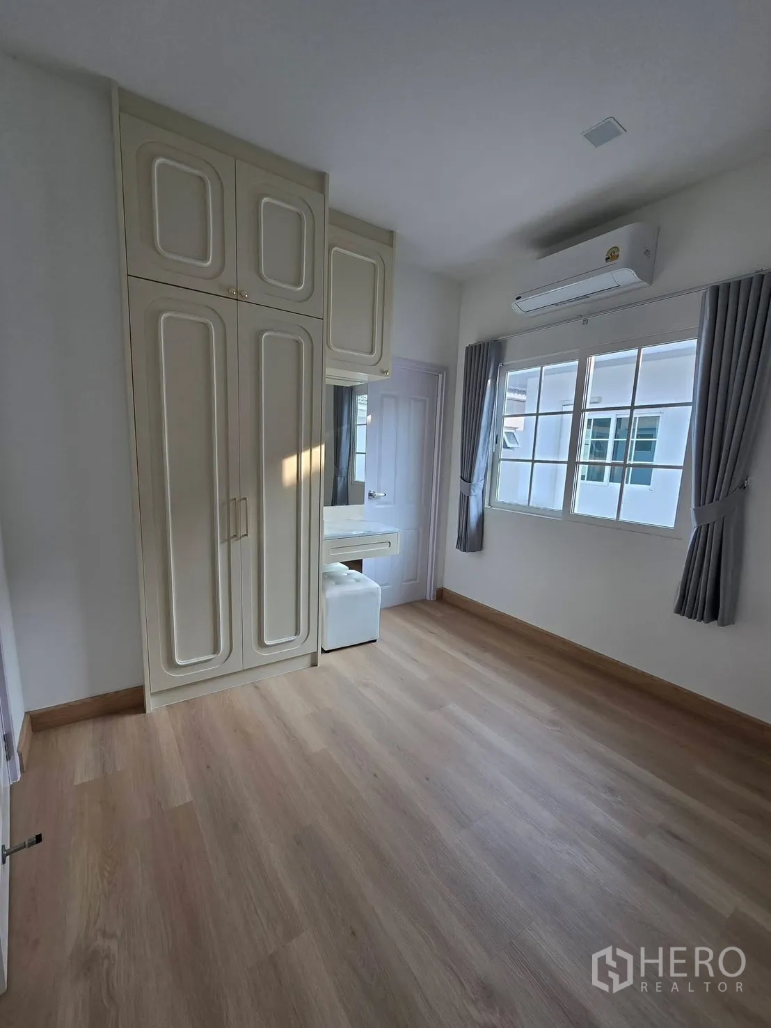 Semi-detached House for rent in Mueang Samut Prakan, Samut Prakan - Bedroom with built-in wardrobes, dressing table, air conditioning and wood-look flooring.