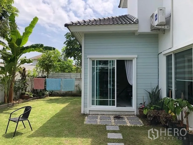 บ้าน ขายในMin Buri, Bangkok - ลานข้างบ้านมีประตูกระจกบานเลื่อน เปิดสู่สนามหญ้าและกำแพงกั้นความเป็นส่วนตัว