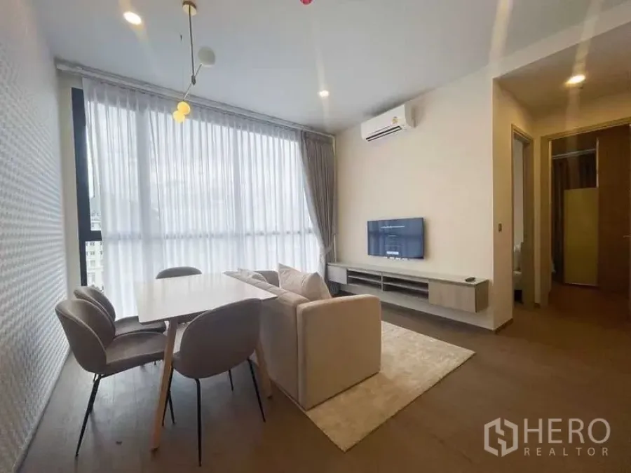 公寓 出租在Ratchathewi, Bangkok - 开放式客厅，沙发、餐桌、电视柜、空调与整面落地窗。