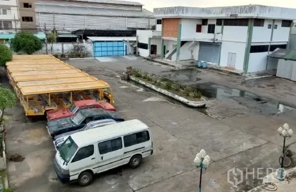 工厂 出售在Bang Phli, Samut Prakan - 俯瞰宽阔的混凝土场地，停放多辆车辆与长形棚架。