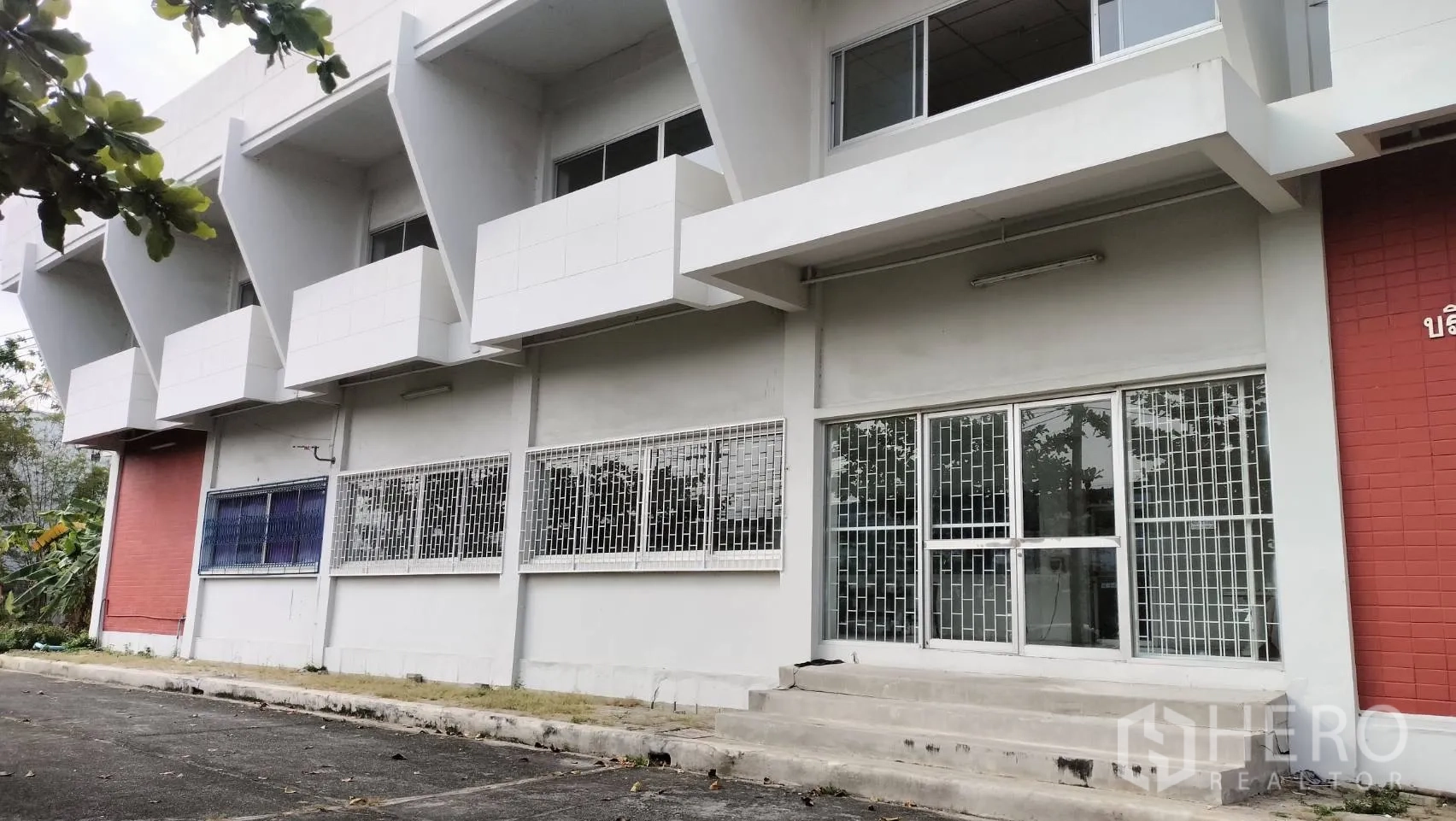 โรงงาน for rent in Lat Krabang, Bangkok - ด้านหน้าอาคารมีเหล็กดัดและบันไดขึ้นสู่ประตูกระจก.