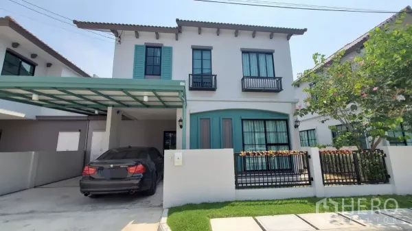 บ้าน ให้เช่าในLat Krabang, Bangkok - หน้าบ้านสองชั้นพร้อมกันสาดที่จอดรถ 2 คัน บานหน้าต่างสีเขียวอมฟ้าและสวนหย่อมด้านหน้า