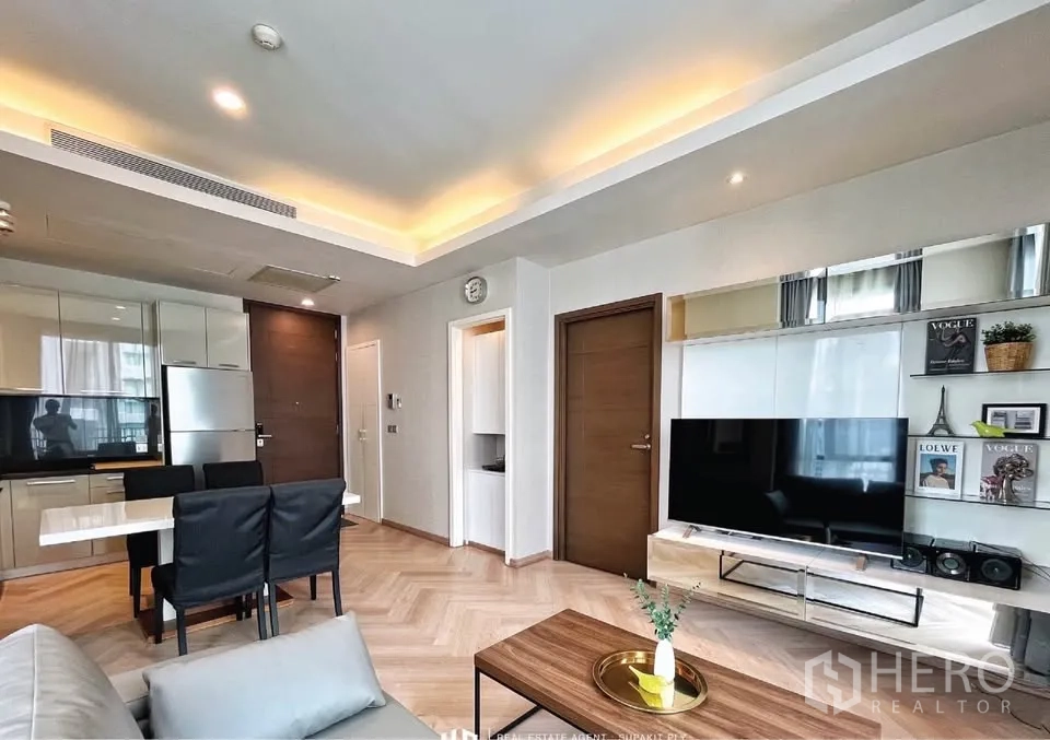 Condominium for rent in Watthana, Bangkok - Open-plan lounge with TV wall, dining set and glossy kitchen cabinets.