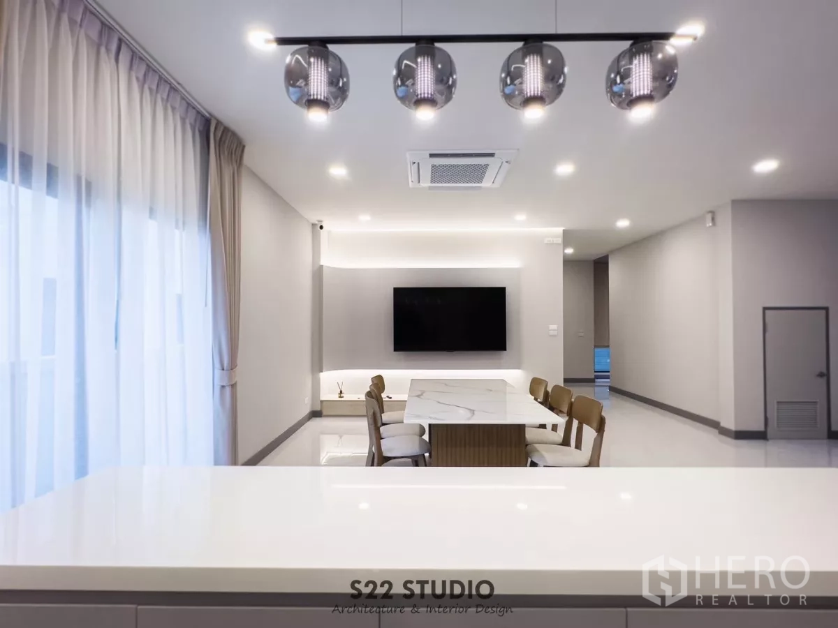 独立式住宅 出租在Bang Phli, Samut Prakan - 餐厅配大理石餐桌与吊灯，通向明亮的起居区与电视墙