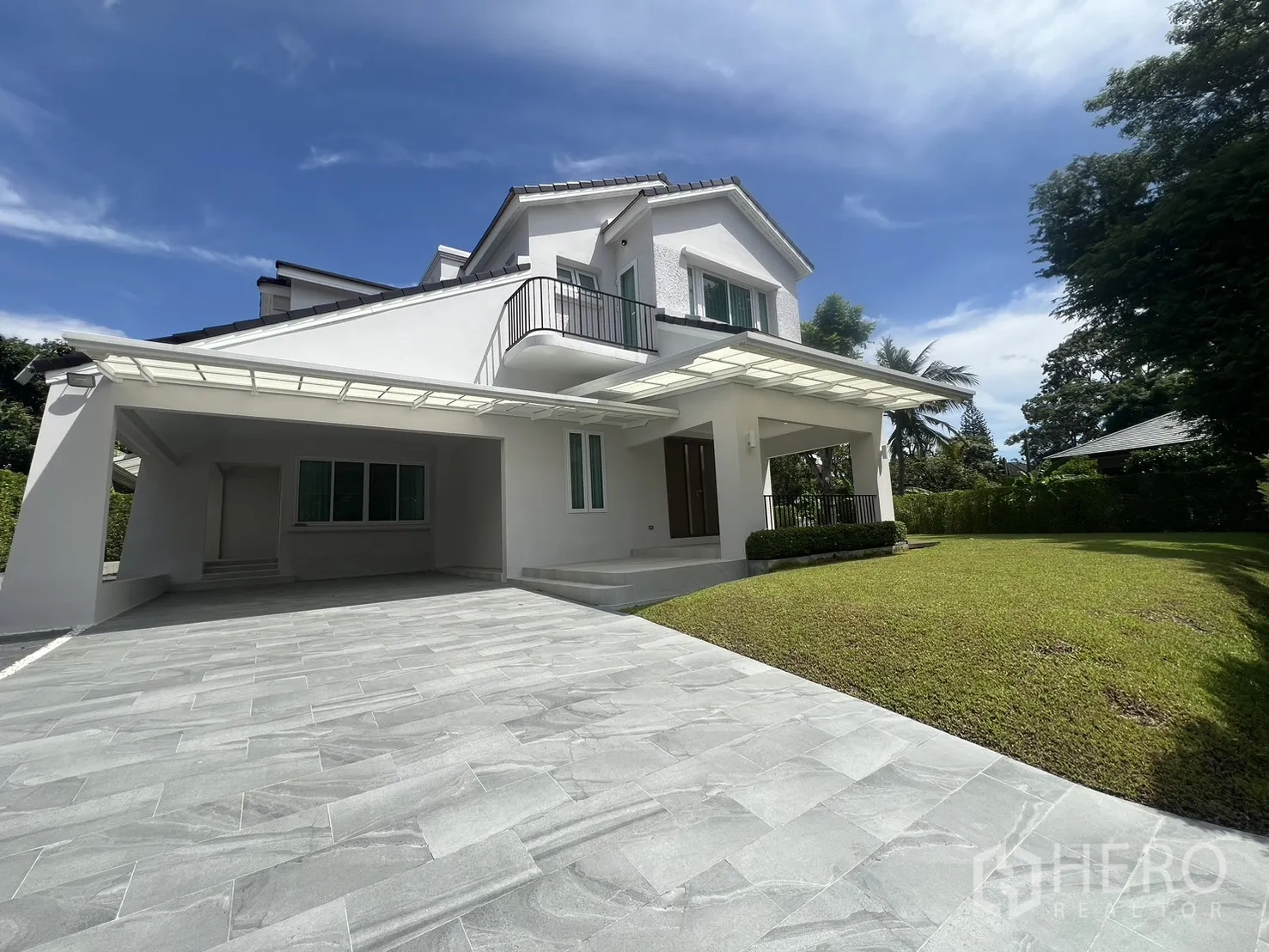 Detached House for rent in Mueang Samut Prakan, Samut Prakan - Wide tiled driveway with covered carport and a green front lawn beside the house.