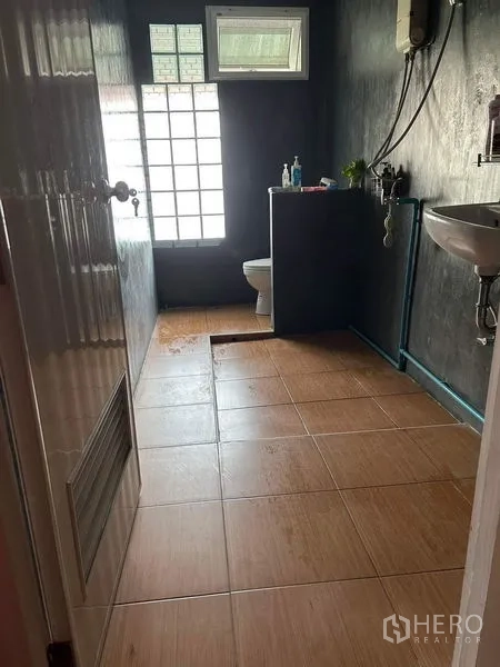店屋 出租或出售在Watthana, Bangkok - 浴室，棕色地砖、玻璃砖采光窗、坐便和洗手盆。