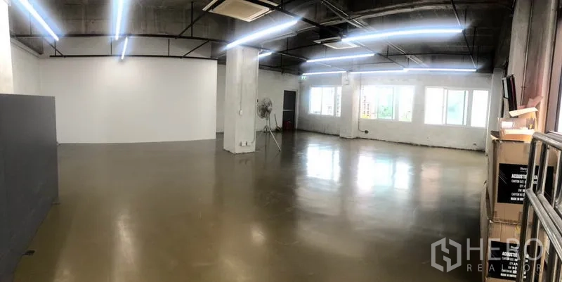 Office Space for rent in Khlong Toei, Bangkok - Open office with wide windows, strip lighting, concrete ceiling and stacked boxes near the entrance