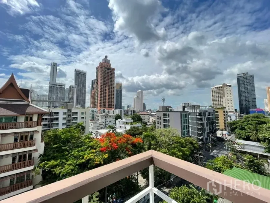 Condominium for rent in Khlong Toei, Bangkok - High-floor balcony view of Khlong Toei skyline with lush trees and dramatic clouds.