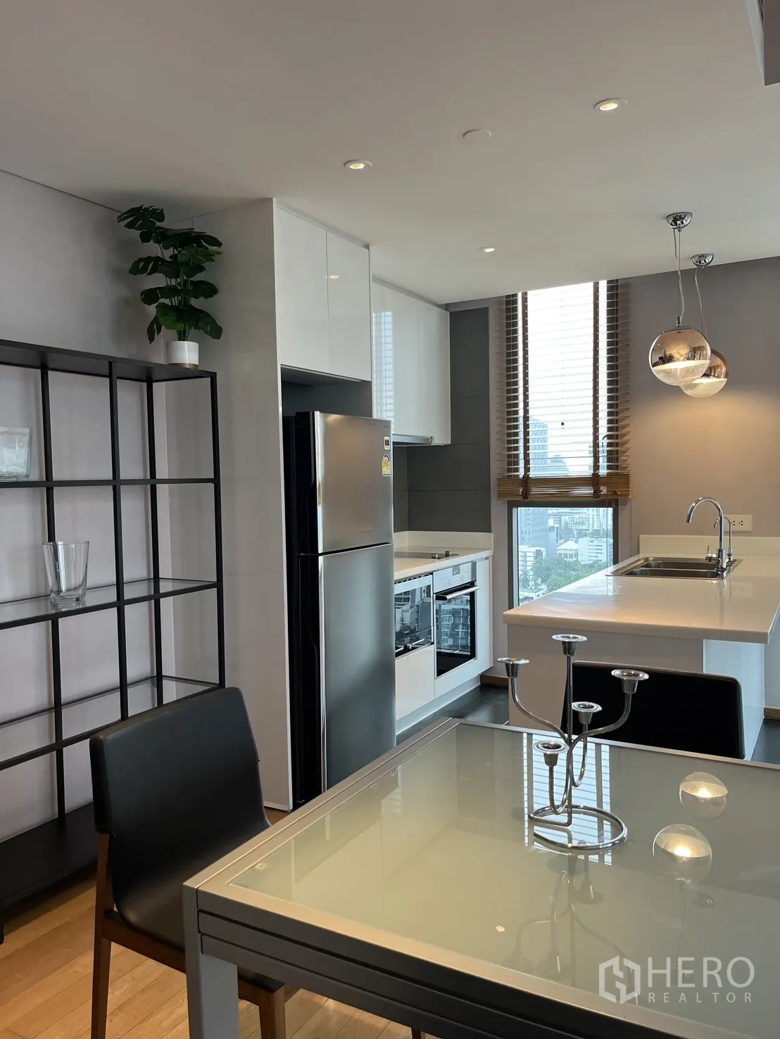 Condominium for rent in Watthana, Bangkok - Dining table beside shelving and a modern kitchen with built-in appliances.