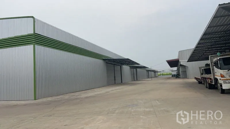 Warehouse for rent in Pathum Thani - Side view of warehouse row featuring metal canopies and roll-up doors designed for logistics operations.