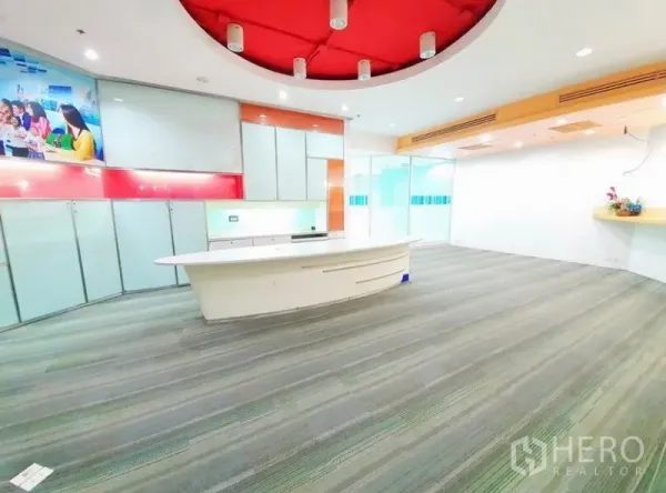 Office Space for rent in Bang Na, Bangkok - Spacious reception area with a curved white counter, red circular ceiling feature and carpet flooring.