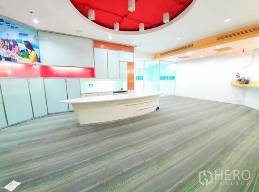 Office Space for rent in Bang Na, Bangkok - Spacious reception area with a curved white counter, red circular ceiling feature and carpet flooring.