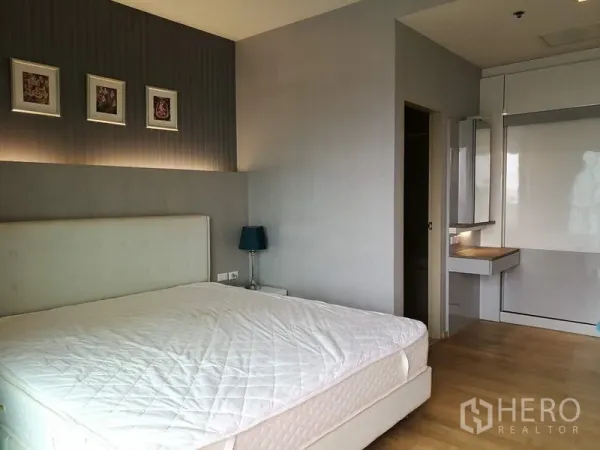 Condominium for rent in Watthana, Bangkok - Bedroom view with feature wall lighting, bedside table and built-in closet with dressing desk.