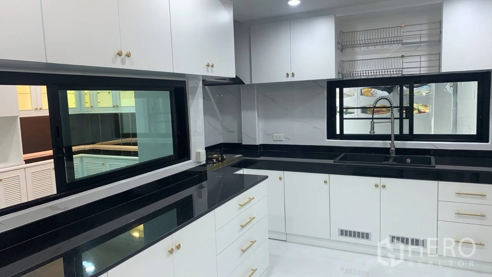 Detached House for rent in Lat Phrao, Bangkok - Bright kitchen with white cabinets, black stone countertops and sink.