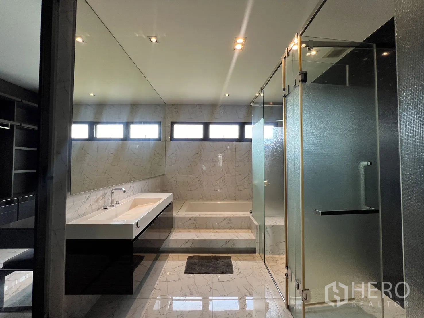 Townhouse for rent in Lat Phrao, Bangkok - Bright upper walkway around skylit atrium with glass balustrade.