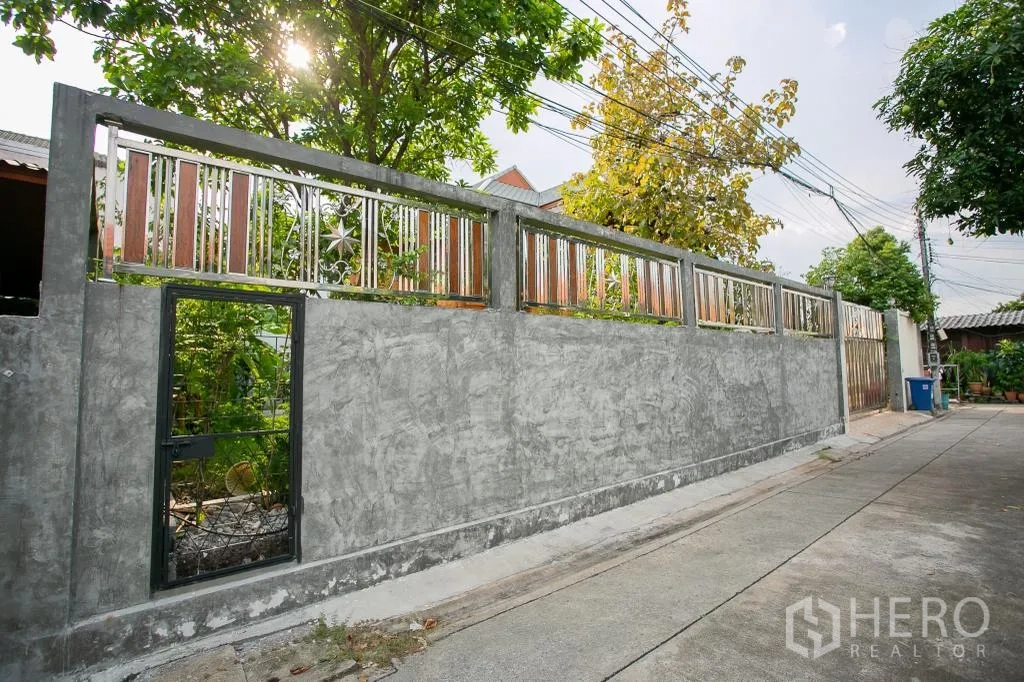 独栋房屋 for rent or sale in Huai Khwang, Bangkok - 坚固的混凝土围墙，带装饰金属栏与行人小门。