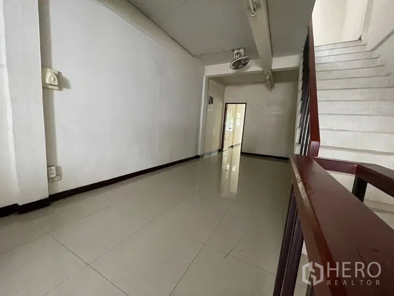 Shophouse for rent in Phra Khanong, Bangkok - Mid-level corridor with tile floors, stair and doorway to a room.
