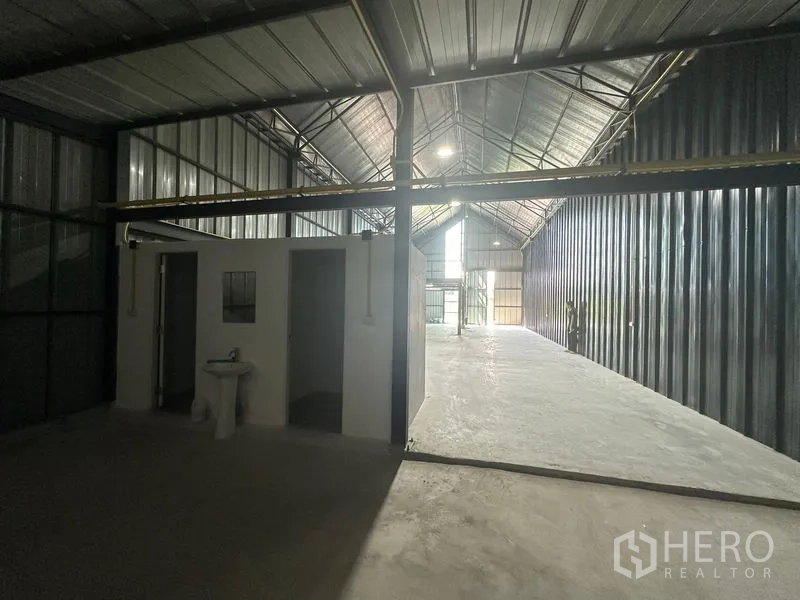 Warehouse for rent in Bueng Kum, Bangkok - Deep warehouse space featuring a built-in restroom block, corrugated metal walls and skylight illumination.