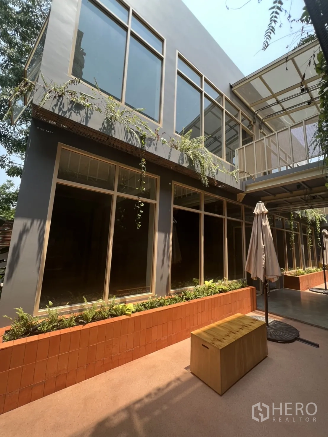 Retail Space for rent in Watthana, Bangkok - Contemporary facade with large windows, balcony and long brick planters along the walkway.