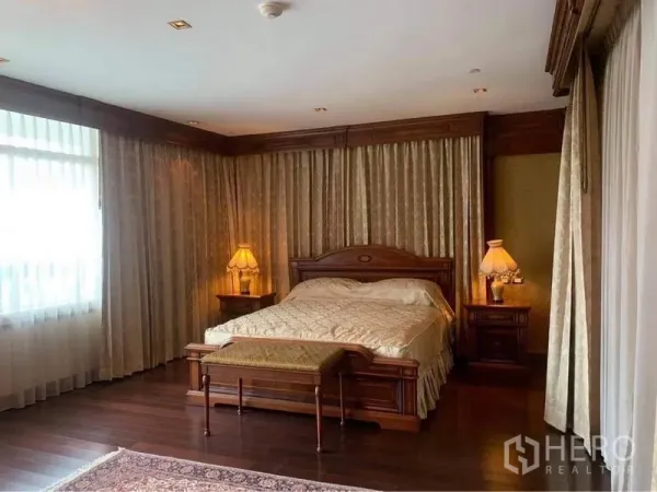 公寓 出租在Watthana, Bangkok - 宽敞主卧，特大床，落地窗帘与实木地板，床尾长凳与床头灯。