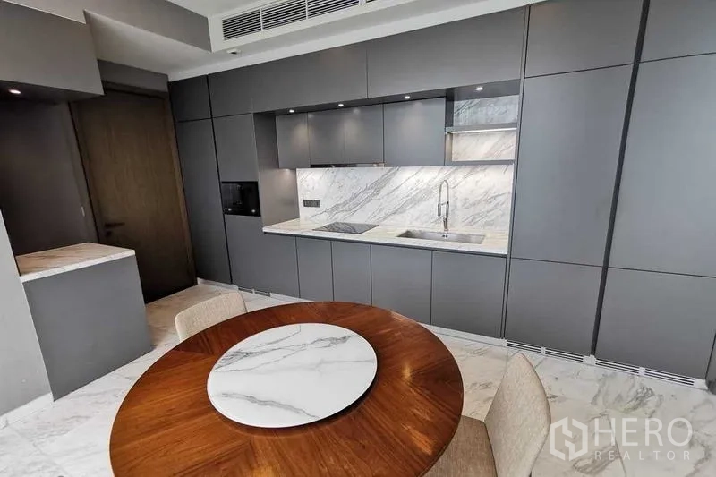 Condominium for rent or sale in Watthana, Bangkok - Sleek kitchen wall with integrated appliances and marble counters.