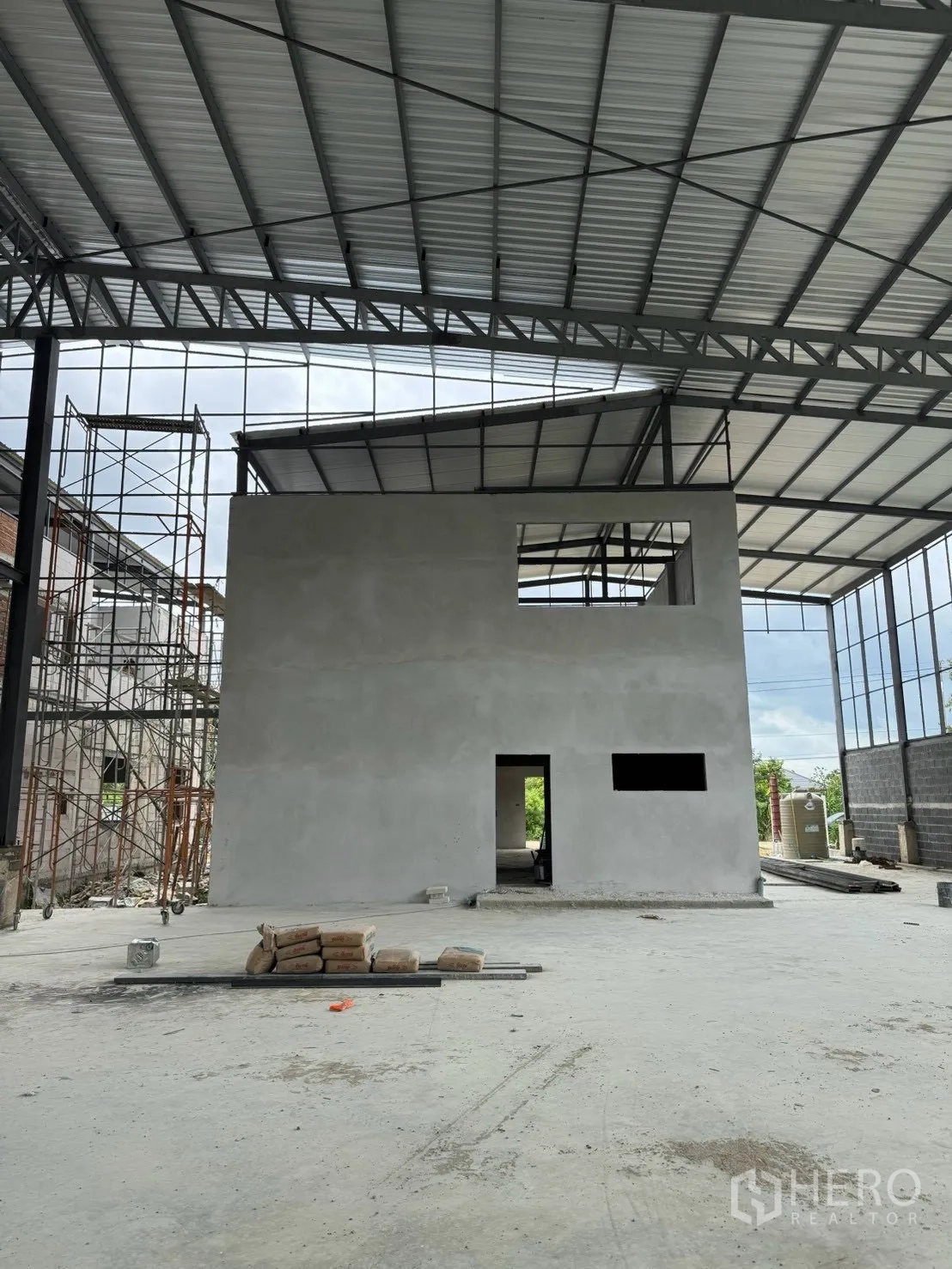 Factory for rent in Phutthamonthon, Nakhon Pathom - Freestanding concrete office block inside the factory with metal roof overhead.