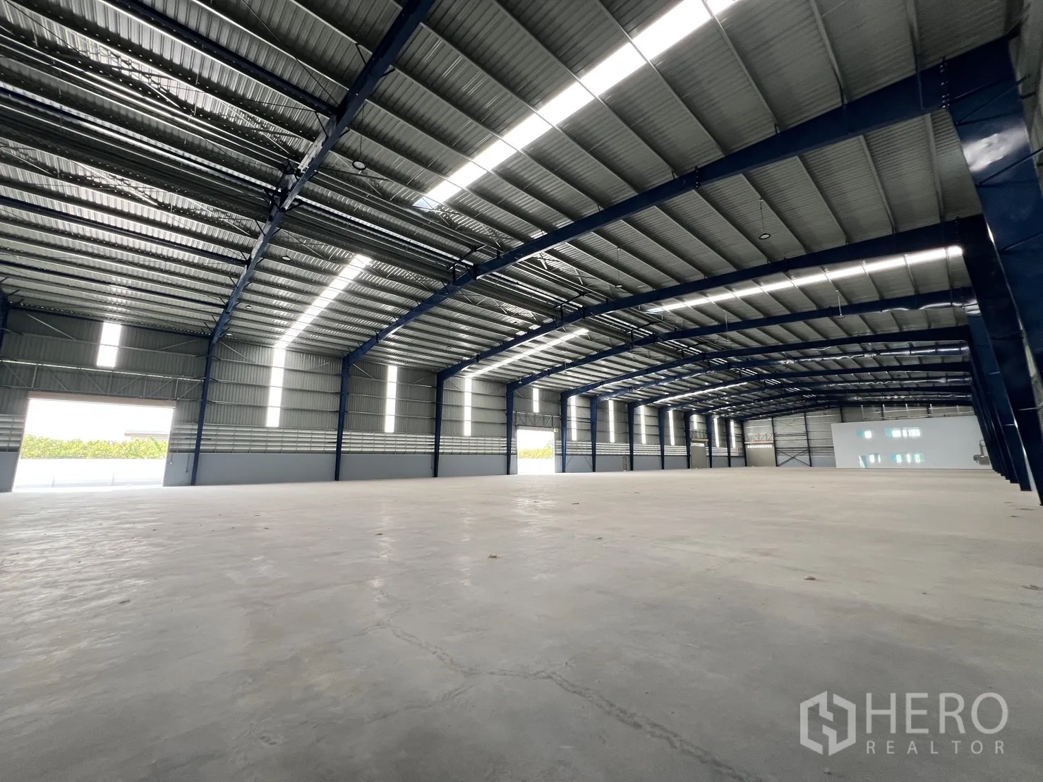 Warehouse for rent in Mueang Samut Prakan, Samut Prakan - Open warehouse floor with polished concrete and wide-span steel beams letting in daylight.