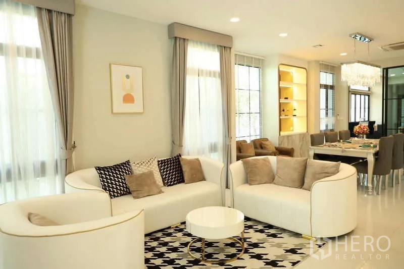 Detached House for rent or sale in Saphan Sung, Bangkok - Cozy lounge with two white sofas, patterned rug and side windows.